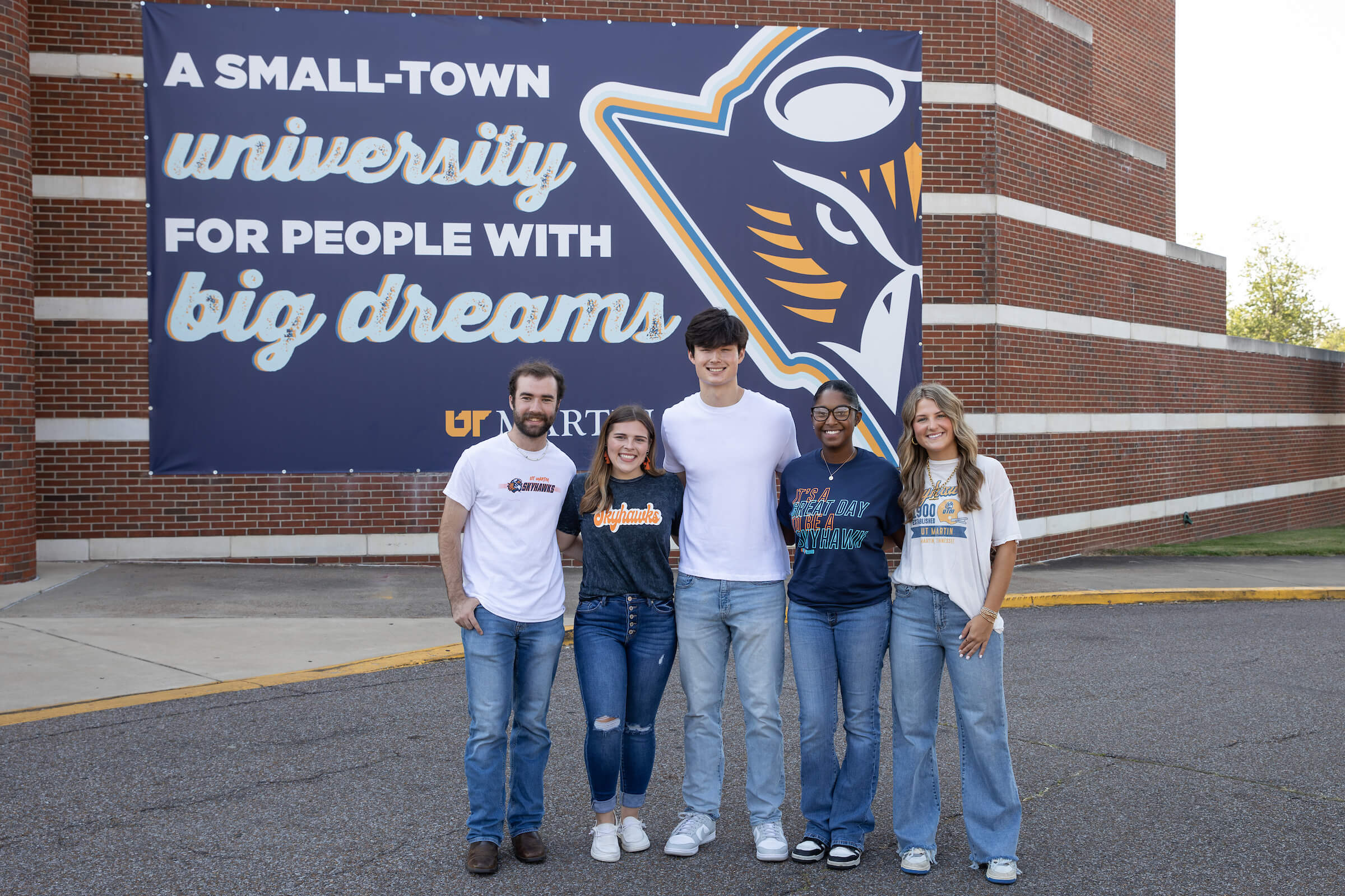 Students posing in front of the Go Skyhawks banner